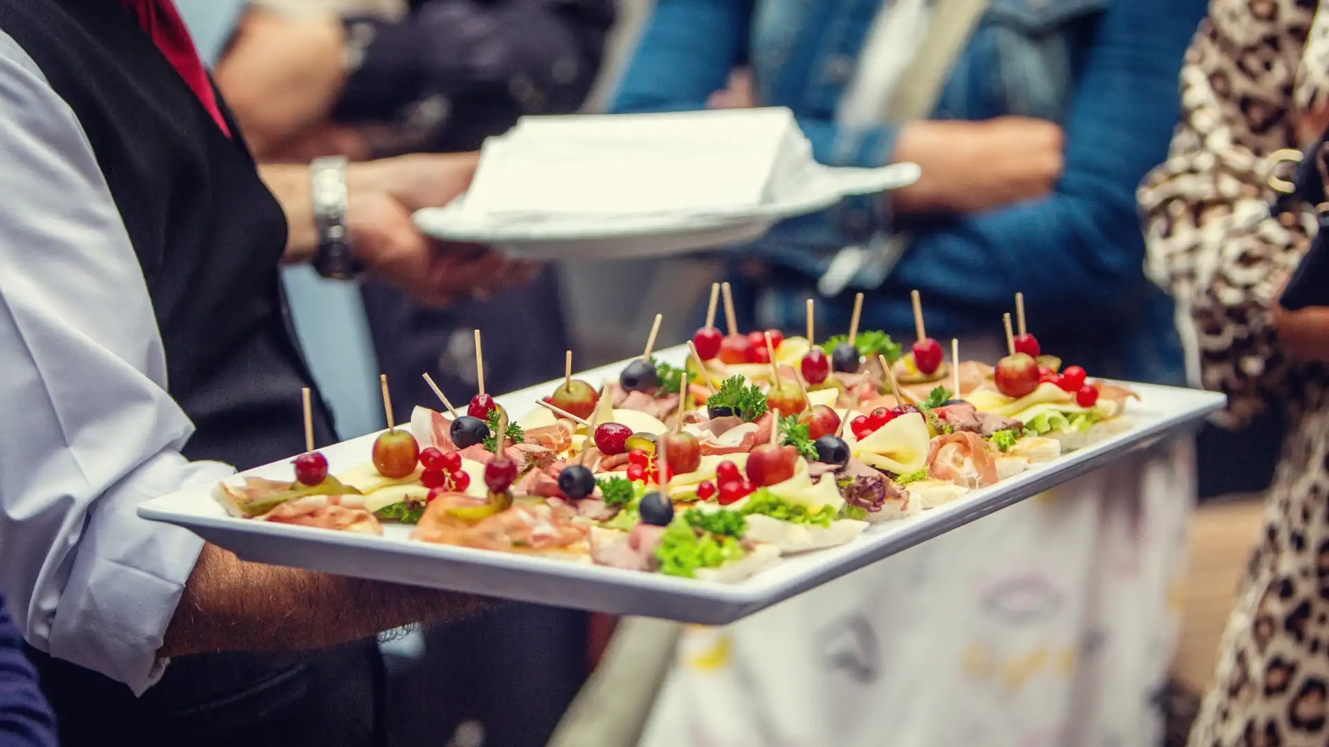 Kellner der Cateringfirma mit einem Tablett voll mit Fingerfood